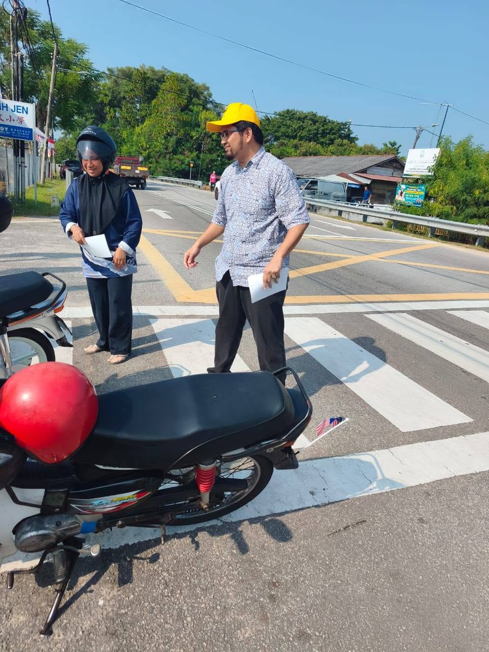 Aman Akil menyapa seorang penunggang motosikal ketika mengedarkan jemputan.