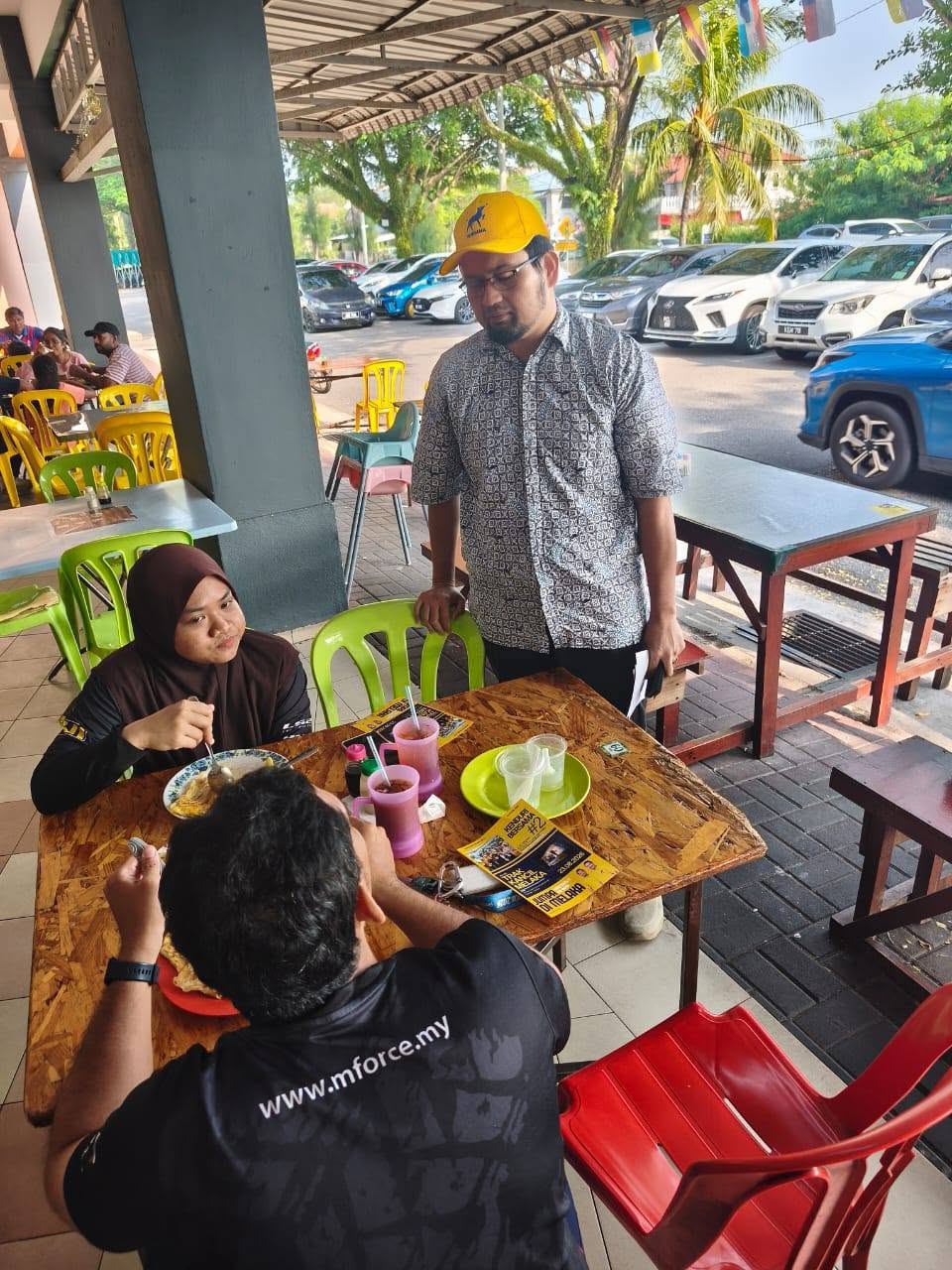 Aman Akil berbual dengan pengunjung di meja makan bersama risalah jemputan.