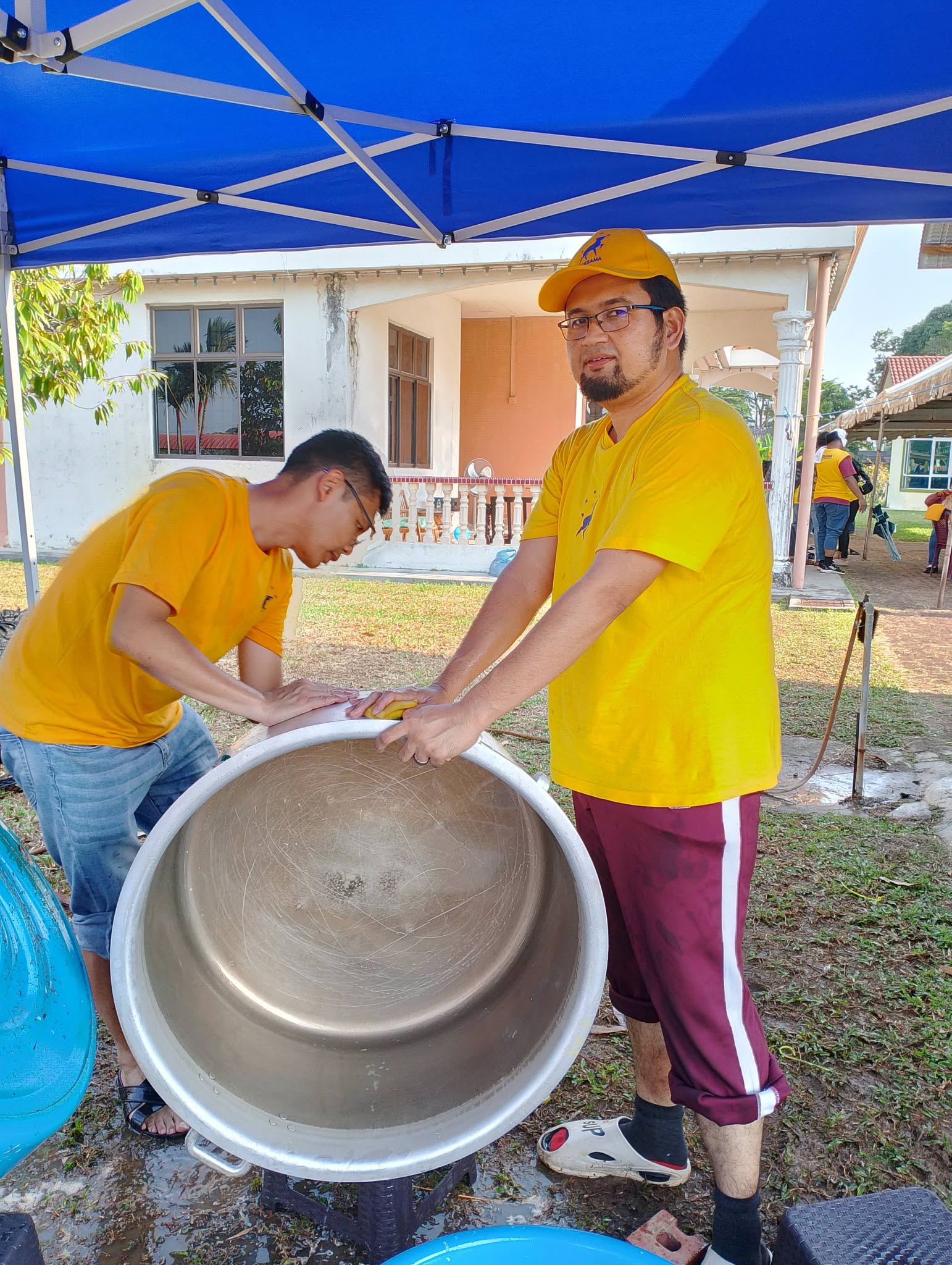 Aman Akil membantu membersihkan bahagian luar periuk bersama seorang ahli pasukan.