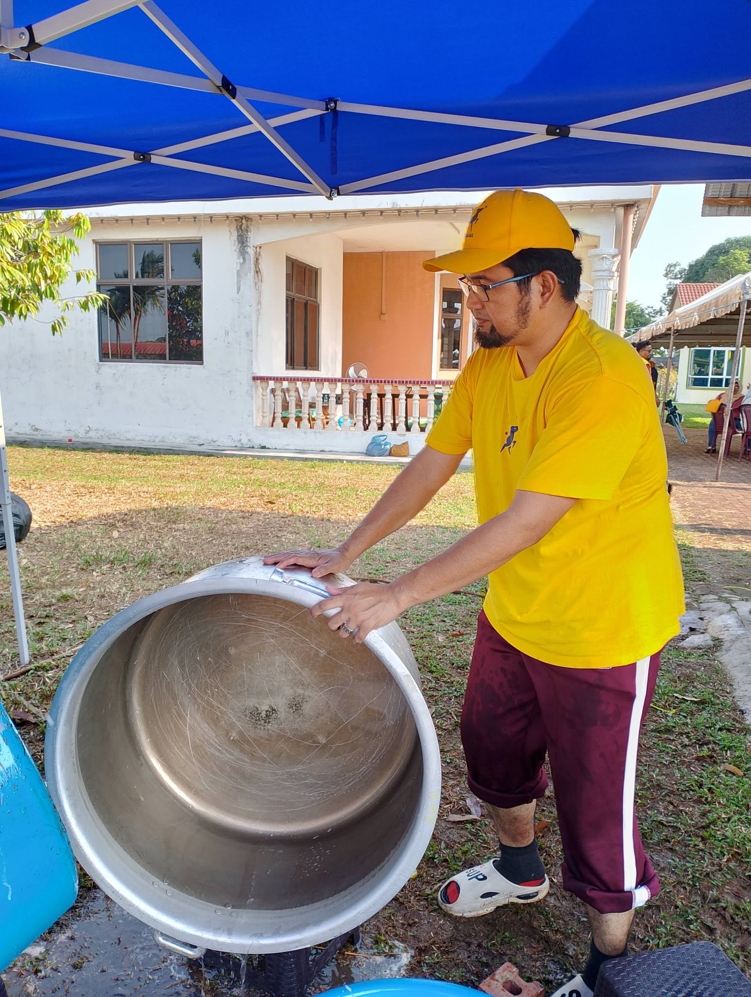 Aman Akil memegang periuk besar ketika kerja membersihkan peralatan kenduri.