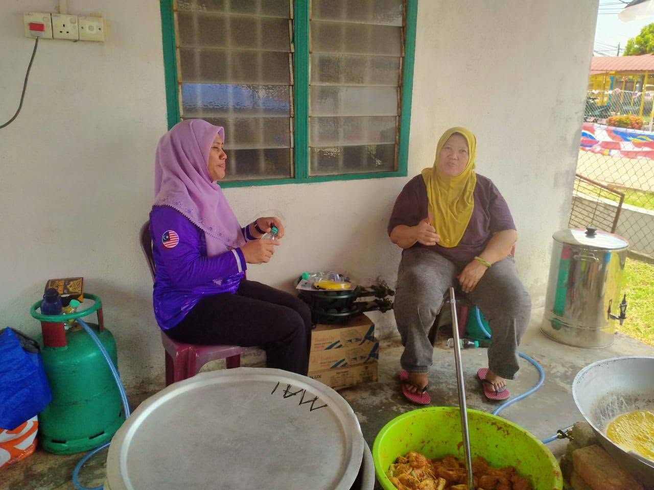 Dua petugas berehat di ruang penyediaan makanan kenduri.